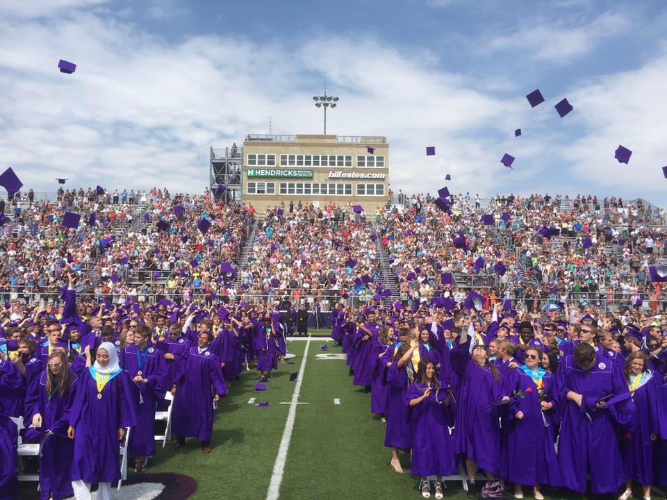 Students toss their caps in the air during a graduation ceremony